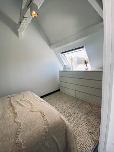 a attic bedroom with a bed and a window at Cinestrings in Mons