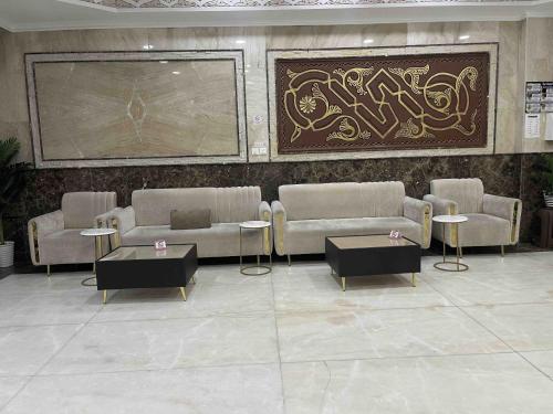 a lobby with couches and tables and a painting on the wall at فندق الأصالة البكية توصيل مجاني الى الحرم - ALAsalah ALBakkiya Hotel Free Shuttel Service in Al Masfalah