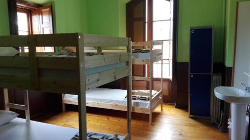two bunk beds in a room with green walls at Albergue La Casona Del Peregrino in Llanes