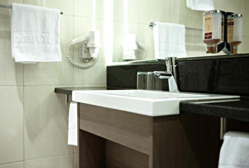 La salle de bains est pourvue d'un lavabo blanc et d'un miroir. dans l'établissement IntercityHotel Essen, à Essen