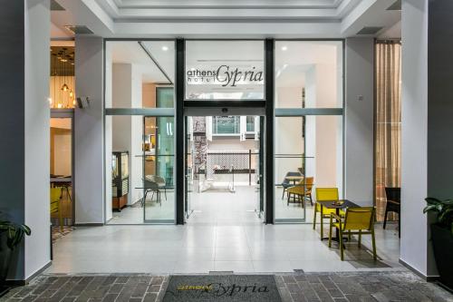 a lobby with glass doors and tables and chairs at Athens Cypria Hotel in Athens