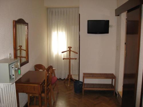 sala de estar con mesa y TV en la pared en Hostal Maria Cristina, en Madrid