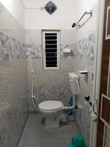a bathroom with a toilet and a window at Bridhi Guest House in Siliguri