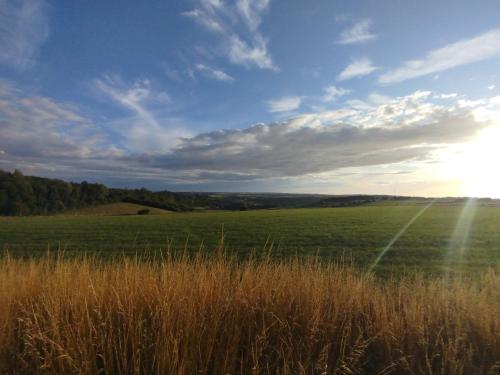 a field of grass with the sun in the sky at Chambre vallée de la course in Parenty