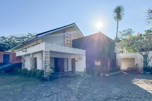 a house with a palm tree in front of it at Villa Anugerah Linggarjati Mitra RedDoorz in Sangkanurip