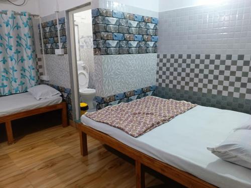 a small room with two beds and a bathroom at Bridhi Guest House in Siliguri