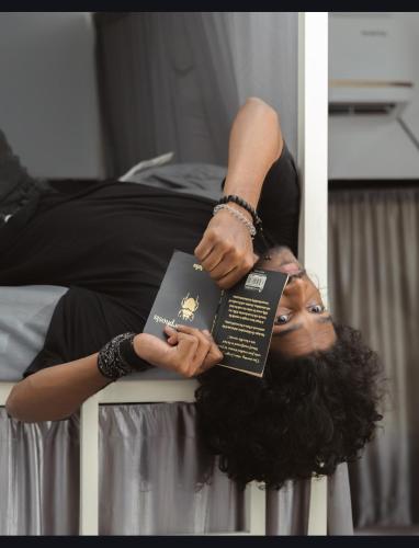 a woman laying on a bed holding a book at Half Orangee Party Stay with Free Swimming Pool, Free Game Room, Free Parking Next to Vagator Beach-Near to Chapora Fort-Near to Hill Top -Best for Couples-Backpackers, Long stays, Coworking, Day-use with Game zone and summer vacation!! in Vagator