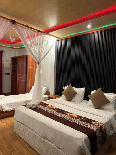 two beds in a hotel room with a rainbow above them at Nika Inn Himandhoo in Himandhoo 