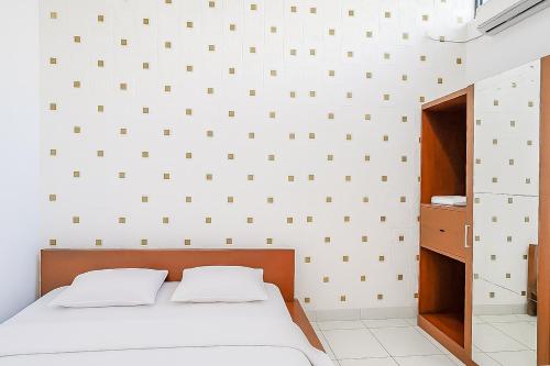 a bedroom with a bed and a white wall at Villa Anugerah Linggarjati Mitra RedDoorz in Sangkanurip