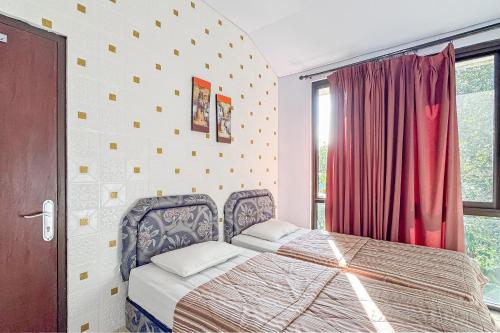 a bedroom with a bed in front of a window at Villa Anugerah Linggarjati Mitra RedDoorz in Sangkanurip