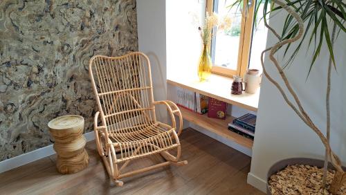 einem Schaukelstuhl aus Rattan in einem Zimmer mit Fenster in der Unterkunft Le Foyer Celtique in Ploërmel