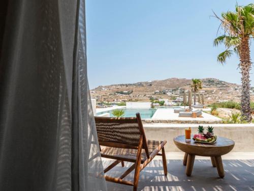 a chair and a table on a balcony with a view at Adama Mykonos Boutique Hotel in Mýkonos City