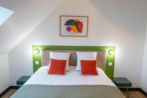 a bedroom with a bed with two red pillows at L'Escapade d'Acquigny, Piscine, Foot Five, Salle de sport, BabyFoot in Acquigny
