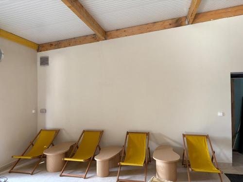 a group of yellow chairs in a room with a wall at L'Escapade d'Acquigny, Piscine, Foot Five, Salle de sport, BabyFoot in Acquigny