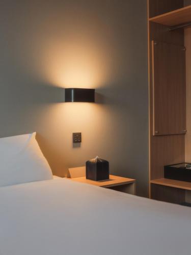 a bedroom with a bed and a light on the wall at Urbanstay Hotel Dongtan in Hwaseong