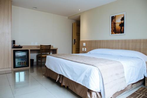 a bedroom with a large bed and a desk at Elegance Praia Hotel in Rio de Janeiro