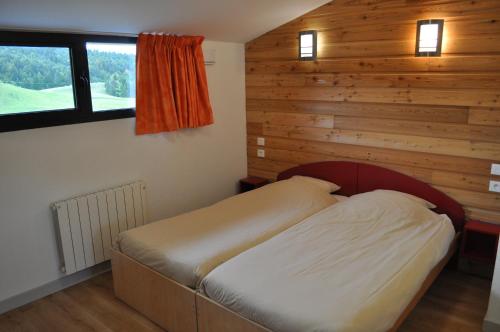 a bed in a room with a wooden wall at Village Vacances Passion Georges Moustaki in Les Moussières