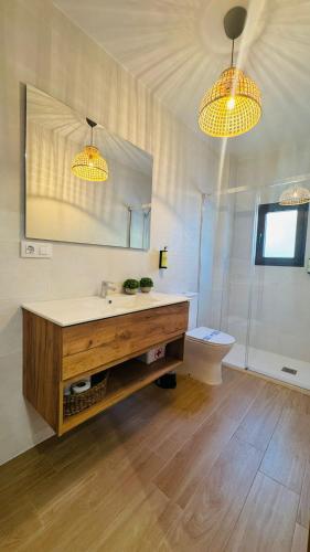a bathroom with a sink and a toilet and two lights at Apartamentos Ladera del Castillo in Cazorla