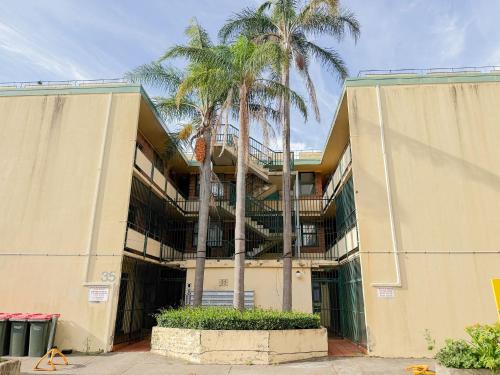 a building with palm trees in front of it at Burwood Cozy Studios in Sydney