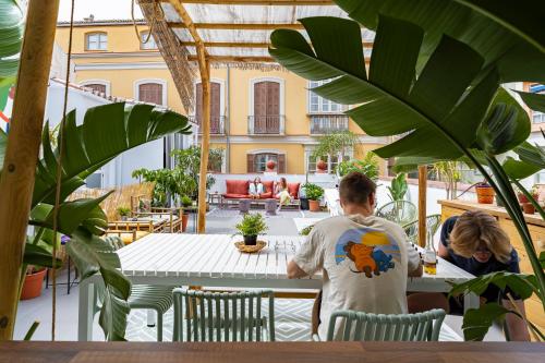 mężczyzna i kobieta siedzący przy stole na patio w obiekcie The Urban Jungle Hostel w Maladze