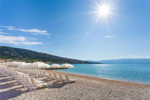 a row of chairs and umbrellas on a beach at Victoria Camping Baška Beach in Baška