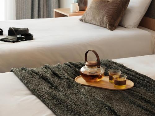 a tray with two glasses of honey on a bed at Urbanstay Hotel Dongtan in Hwaseong