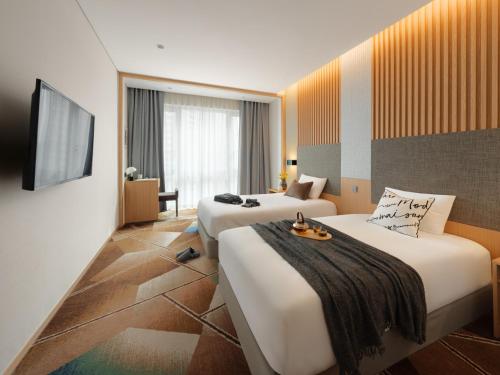 a hotel room with two beds and a flat screen tv at Urbanstay Hotel Dongtan in Hwaseong