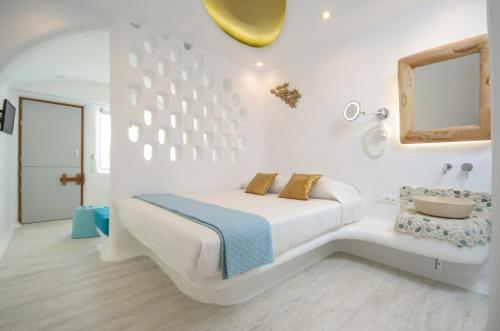 a white bedroom with a bed and a chair at Orkos Beach Hotel in Mikri Vigla
