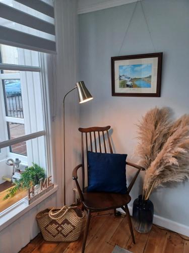 a chair with a blue pillow in a room with windows at Beachside Terrace in Dovercourt