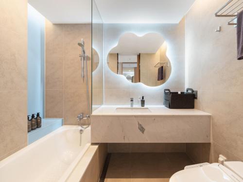 a bathroom with a sink and a tub and a mirror at Urbanstay Hotel Dongtan in Hwaseong