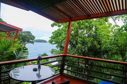a balcony with a table and a view of the water at Mom Tri's Villa Royale - SHA Plus in Kata Beach