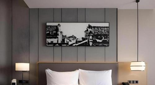 a hotel room with a bed with a picture above it at Zhuhai Tangyi Hotel in Zhuhai