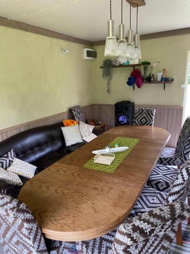 a living room with a wooden table and a leather couch at Metsanõmme saunamaja in Lümati