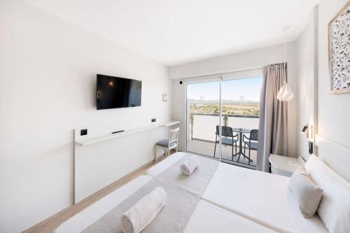 a white bedroom with a large bed and a balcony at Hotel Ankaa - Adults Only in Porto Cristo