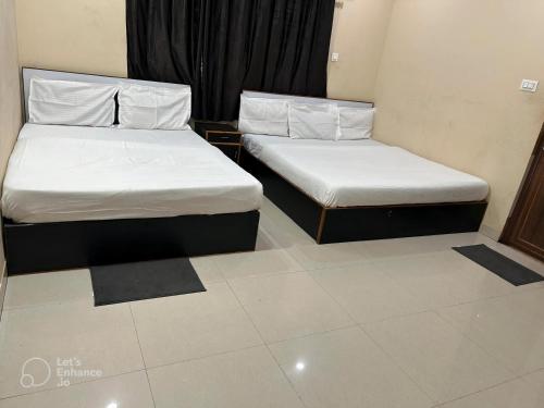 two beds in a hotel room with white sheets at Archie Oasis in Bhubaneshwar