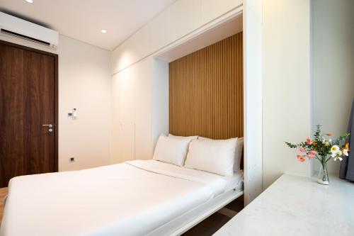 a bedroom with a white bed and a vase of flowers at Convinia Luxury The Peak Midtown -Free Airport Pick Up in Ho Chi Minh City