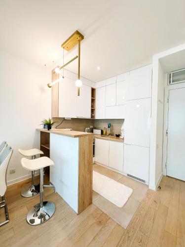 a kitchen with white cabinets and a counter with a stool at SARA Lux A Blok in Belgrade