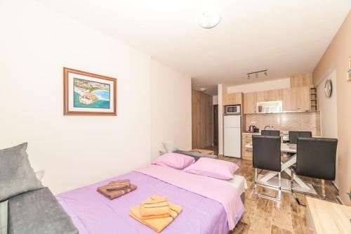 a bedroom with a purple bed and a kitchen at Milara Apartments in Budva