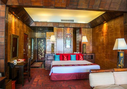 a bedroom with a large bed with red and blue pillows at Mom Tri's Villa Royale - SHA Plus in Kata Beach