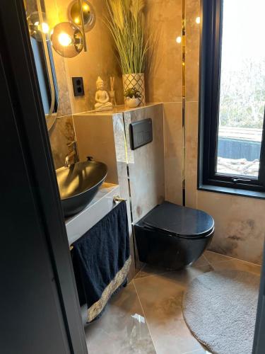 a bathroom with a black toilet and a sink at High standard and beautiful view in Tennevika