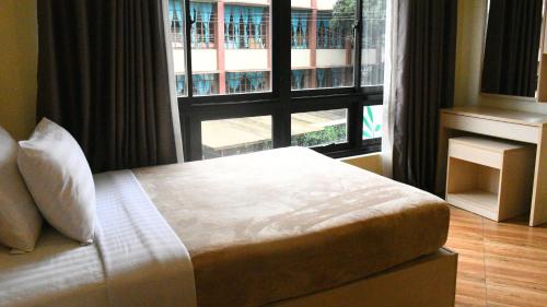 a bedroom with a bed and a large window at Olive Town Center and Hotel in Baguio