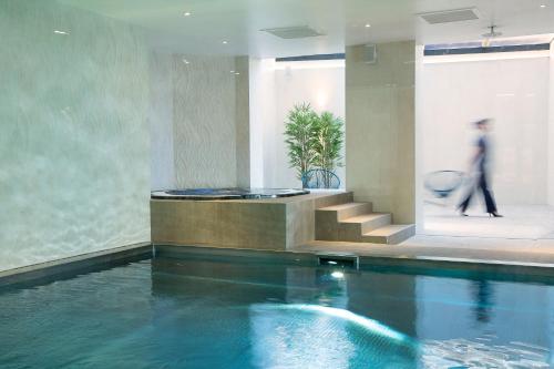 a man walking by a swimming pool in a building at Oceania L'Univers Tours in Tours