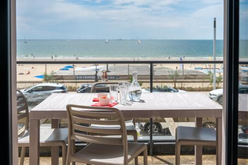 a table with chairs and a view of the beach at Résidence Odalys De La Plage in Pornichet
