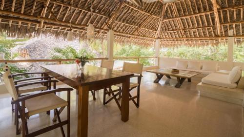 a dining room with a table and chairs and a couch at Palm Garden ECO Boutique Hotel No Kids under 12 in Watamu