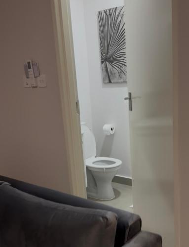 a bathroom with a toilet and a chair in a room at The Fig Studio Apartment-A203 in Gaborone
