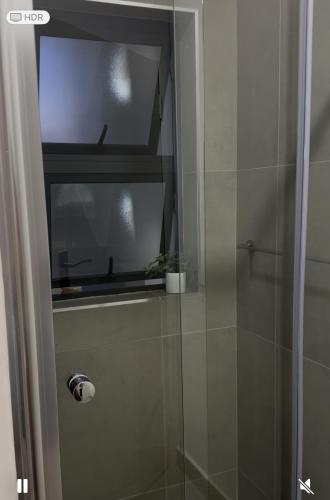 a glass shower door with a window in a bathroom at The Fig Studio Apartment-A203 in Gaborone