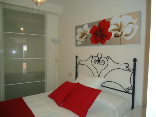 una camera da letto con un letto con una coperta rossa e fiori sul muro di Apartamentos Acevedo Centro a Ronda