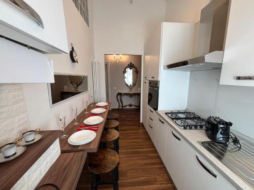 a kitchen with white cabinets and a long table with stools at CAVOUR257 in La Spezia
