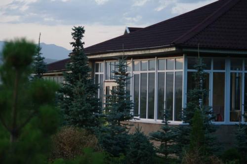 a house with large windows and trees in front of it at Кара суу in Akchiy