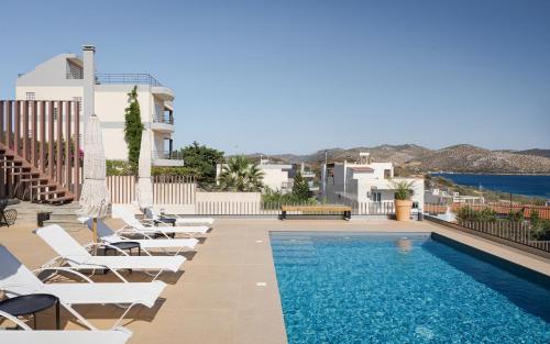 una piscina con sedie a sdraio accanto a un edificio di Villa Nefeli Athenian Riviera ad Anávissos
